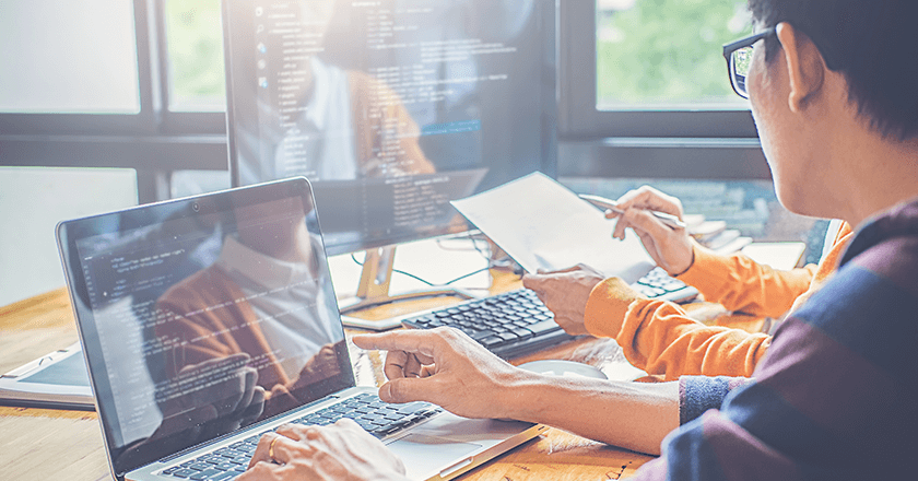 young man providing analytics consulting to a woman at a computer