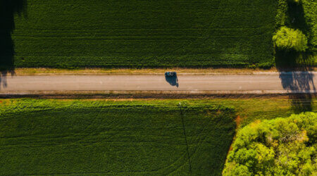 aerial view of a car on a quiet road in an agrarian landscape