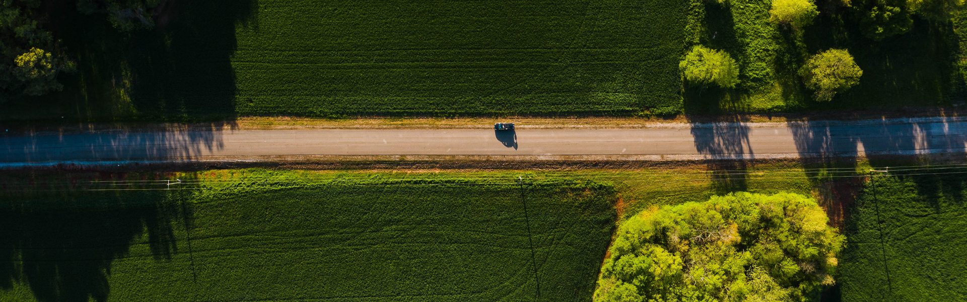 aerial view of a car on a quiet road in an agrarian landscape