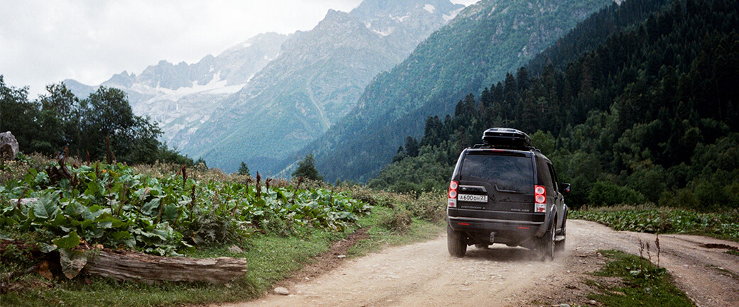 an SUV drives towards the mountains on a dirt road; trailblaze