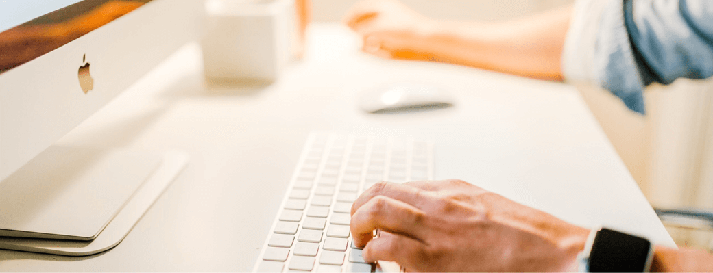 A person sits at a desk and types using a computer keyboard