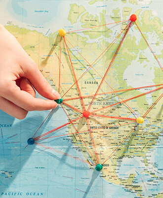 a hand places pins on a map; the pins are networked together with string