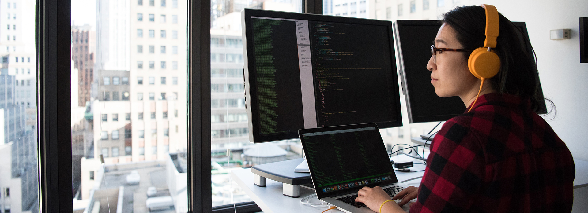 A person works at a computer station and looks out the window pensively