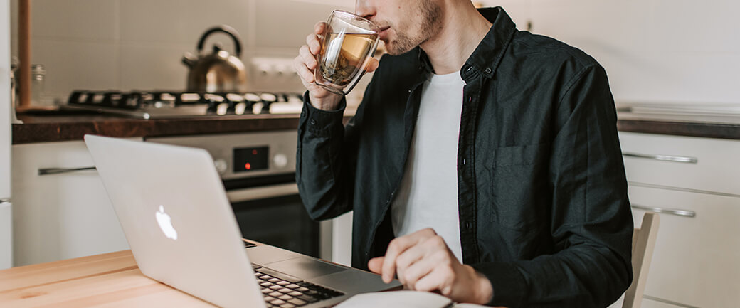 A man uses his laptop while drinking tea