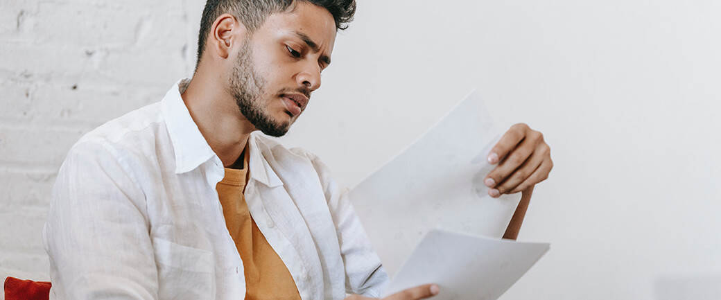 A man looks at some documents with a look of uncertainty on his face